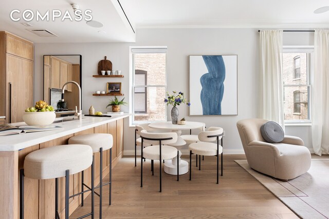 dining room with baseboards, ornamental molding, and light wood-type flooring