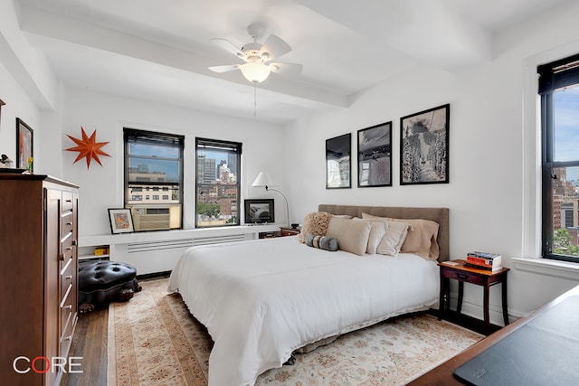 bedroom featuring baseboards, a ceiling fan, wood finished floors, and beamed ceiling