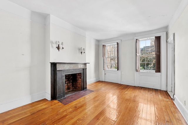 unfurnished living room with baseboards, a fireplace with flush hearth, and light wood-style flooring