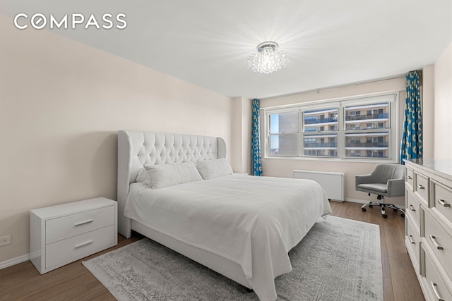 bedroom with radiator heating unit, wood finished floors, and baseboards