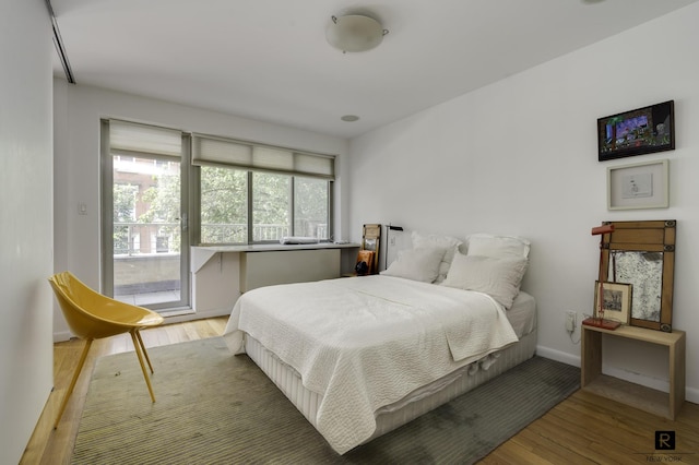 bedroom featuring wood finished floors, access to outside, and baseboards