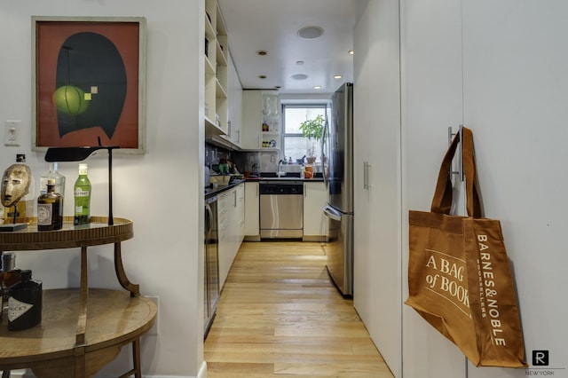 kitchen featuring light wood-style flooring, stainless steel appliances, open shelves, white cabinets, and dark countertops