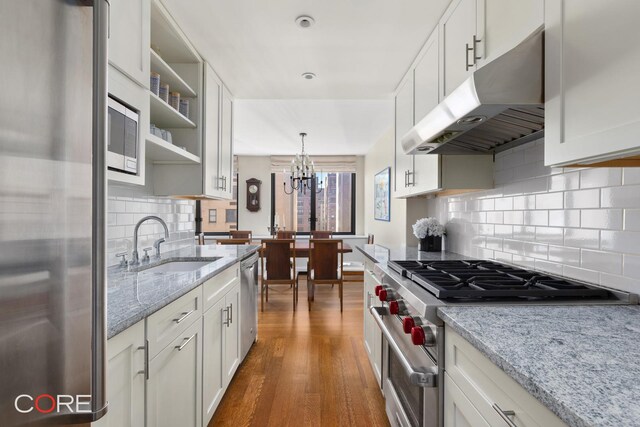 kitchen with appliances with stainless steel finishes, dark wood-type flooring, under cabinet range hood, a sink, and open shelves
