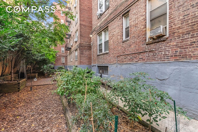 view of property exterior featuring brick siding, cooling unit, and a garden