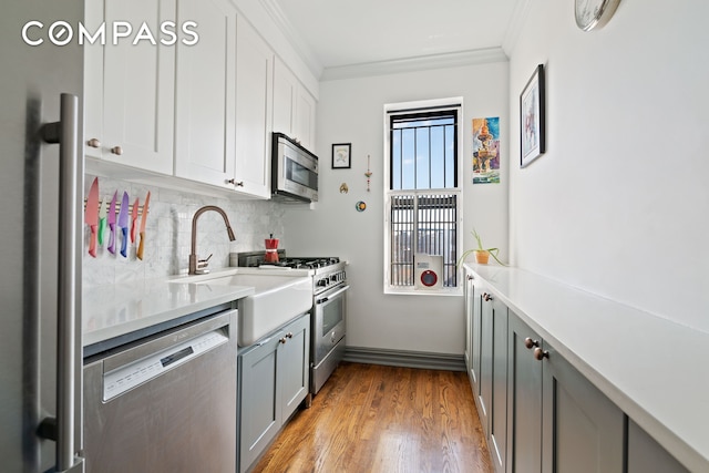 kitchen with stainless steel appliances, crown molding, tasteful backsplash, light countertops, and wood finished floors