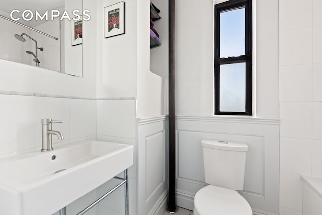 full bath with tile walls, toilet, a sink, and a shower