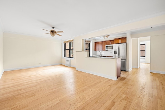 273 Bennett Ave Unit 5-G, New York City, NY 10040 - unfurnished living room with a ceiling fan, crown molding, light wood-style flooring, a sink, and baseboards