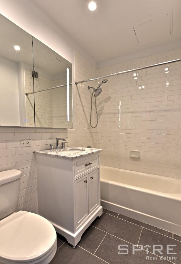 99 John St Unit 2504, New York City, NY 10038 - bathroom featuring tile patterned floors, toilet,  shower combination, vanity, and recessed lighting