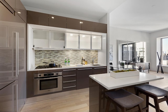kitchen with appliances with stainless steel finishes, a breakfast bar, a sink, light wood-style flooring, and modern cabinets