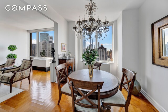 dining area with baseboards, a view of city, and an inviting chandelier