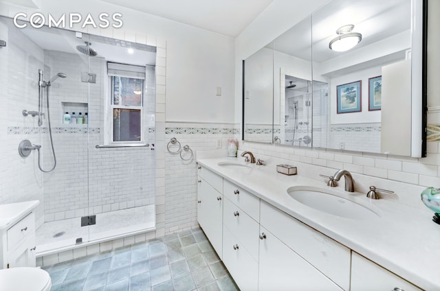 80 E End Ave Unit 3Hj, New York City, NY 10028 - bathroom with double vanity, a stall shower, tile walls, tile patterned floors, and wainscoting
