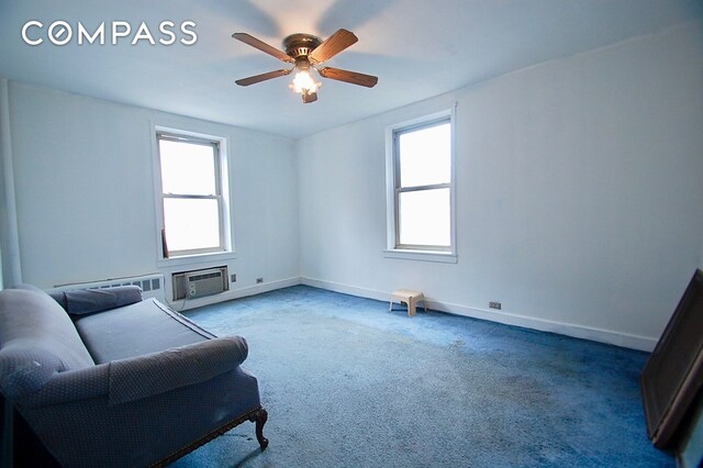 sitting room with a wall mounted air conditioner, ceiling fan, baseboards, and plenty of natural light