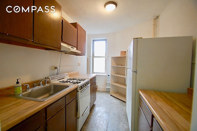 kitchen with light wood-style flooring, a sink, baseboards, white appliances, and under cabinet range hood