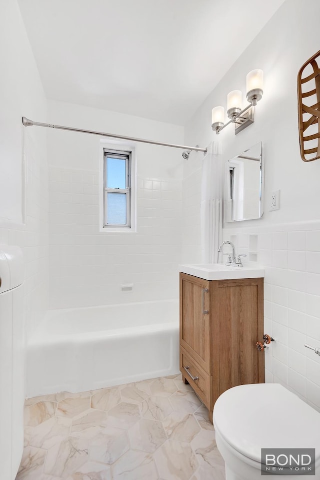 full bath featuring vanity, marble finish floor, shower / bathtub combination, toilet, and tile walls