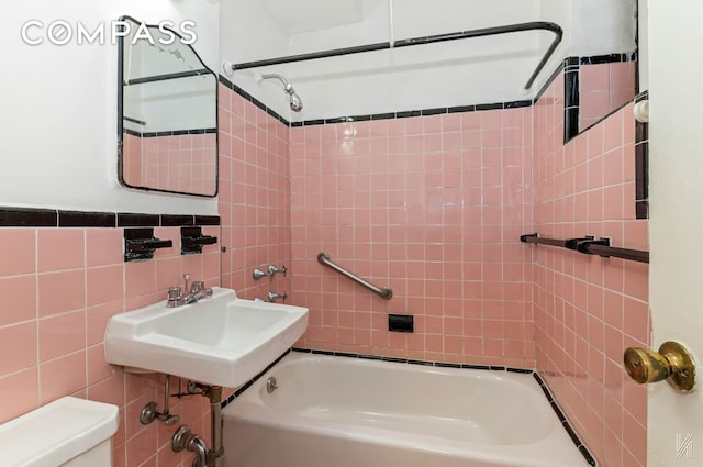 full bath with shower / bathtub combination, toilet, tile walls, and a sink