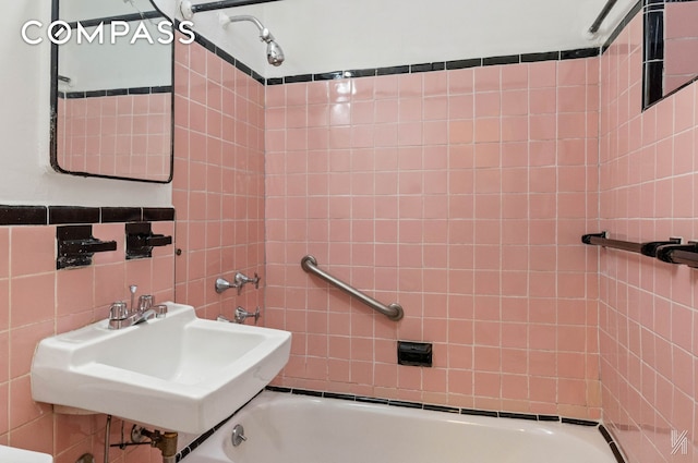 bathroom featuring a sink, tile walls, and washtub / shower combination