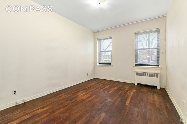 22-60 79th St Unit 1A, New York City, NY 11370 - spare room with radiator heating unit, dark wood-type flooring, and baseboards