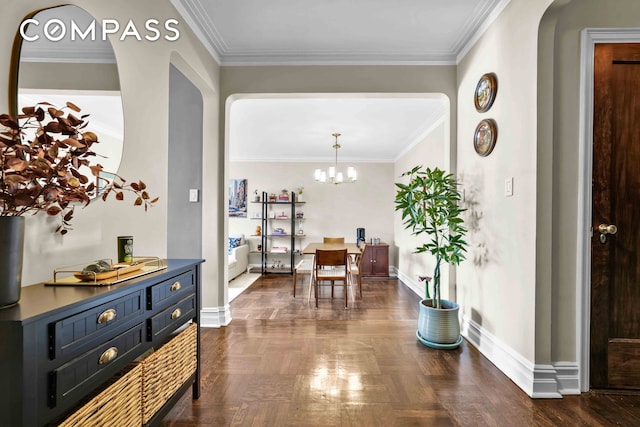 hall with baseboards, a notable chandelier, crown molding, and arched walkways