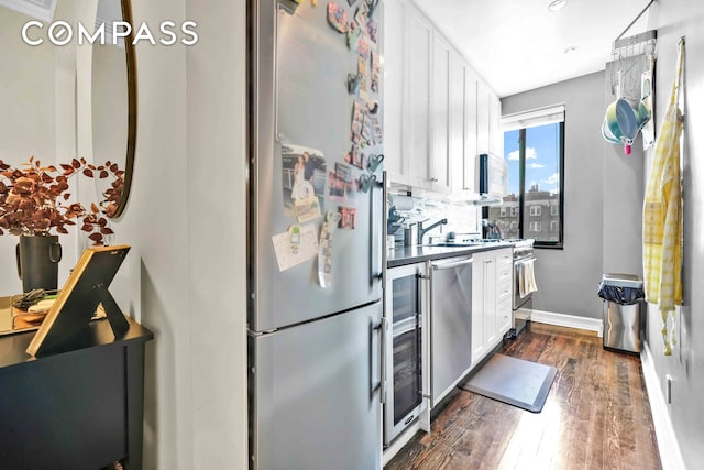 kitchen featuring white cabinets, baseboards, wine cooler, stainless steel appliances, and dark wood-type flooring