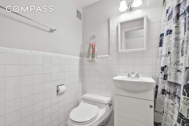 full bath featuring visible vents, tile walls, curtained shower, vanity, and toilet