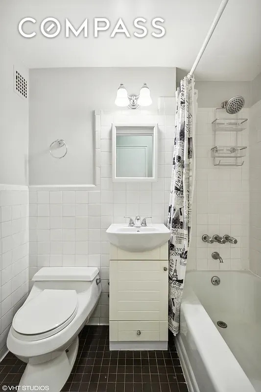 bathroom featuring shower / bath combo with shower curtain, vanity, toilet, tile walls, and tile patterned floors