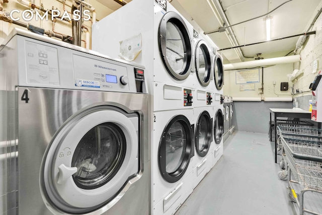 community laundry room with a garage, stacked washer and dryer, and washer and clothes dryer