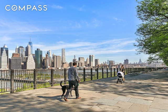 surrounding community featuring a water view, fence, and a city view