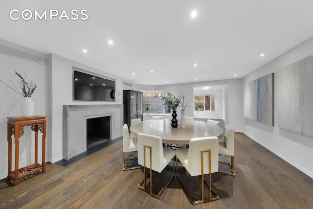 dining space with a fireplace with flush hearth, recessed lighting, baseboards, and dark wood finished floors