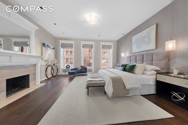 bedroom featuring dark wood-type flooring and a high end fireplace