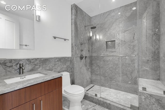 full bath with tile walls, vanity, toilet, marble finish floor, and a marble finish shower