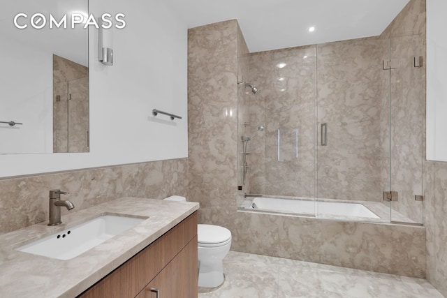 bathroom with toilet, tile walls, combined bath / shower with glass door, and vanity