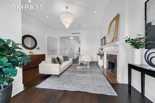 living area featuring visible vents, stairs, wood finished floors, a high end fireplace, and a chandelier
