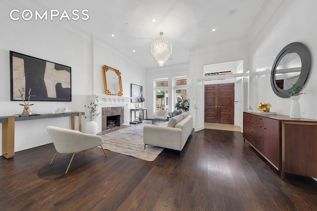 living room featuring dark wood finished floors, baseboards, an inviting chandelier, ornamental molding, and a premium fireplace