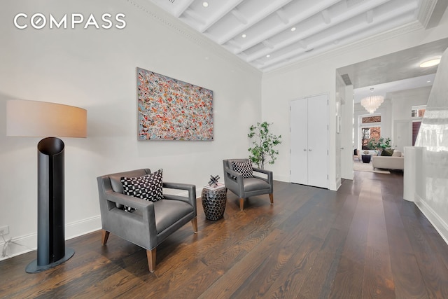 living area with crown molding, a towering ceiling, beam ceiling, and wood finished floors