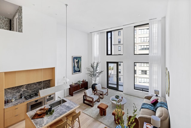 living room featuring a fireplace, a towering ceiling, and light wood-style flooring