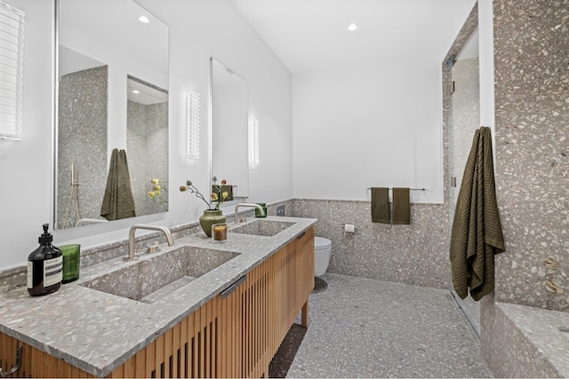 full bathroom with wainscoting, tile walls, a sink, and toilet