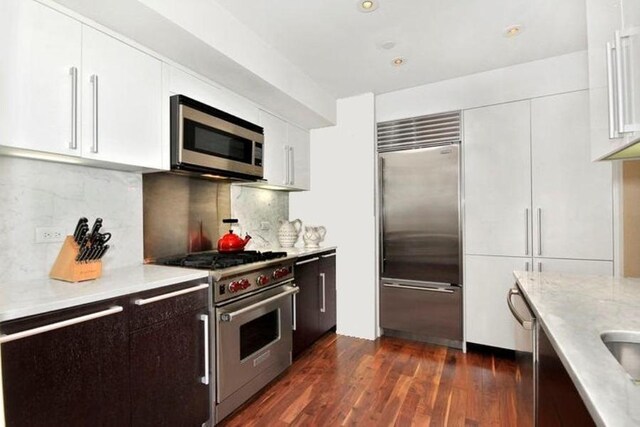 300 E 79th St Unit 5C, New York City, NY 10075 - kitchen featuring decorative backsplash, premium appliances, dark wood-style floors, and white cabinetry