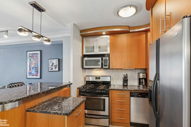 kitchen with tasteful backsplash, dark stone countertops, decorative light fixtures, brown cabinets, and stainless steel appliances