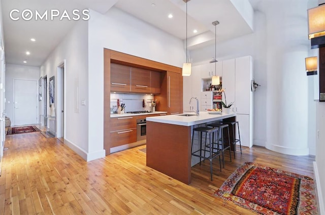360 Furman St Unit 511, New York City, NY 11201 - kitchen featuring stainless steel oven, modern cabinets, brown cabinetry, a breakfast bar, and light wood-style floors