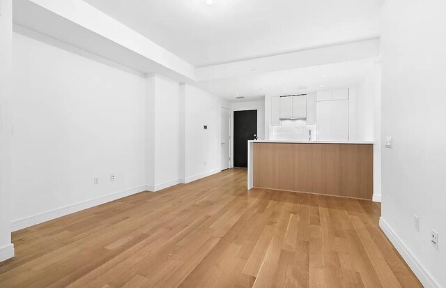 230 E 20th St Unit 11, New York City, NY 10003 - unfurnished living room with light wood-style flooring and baseboards