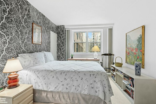 bedroom with carpet flooring, wallpapered walls, and an accent wall