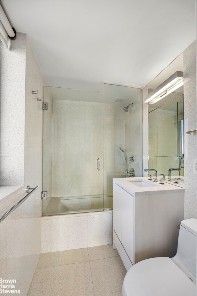 bathroom with visible vents, toilet, vanity, shower / bath combination with glass door, and speckled floor