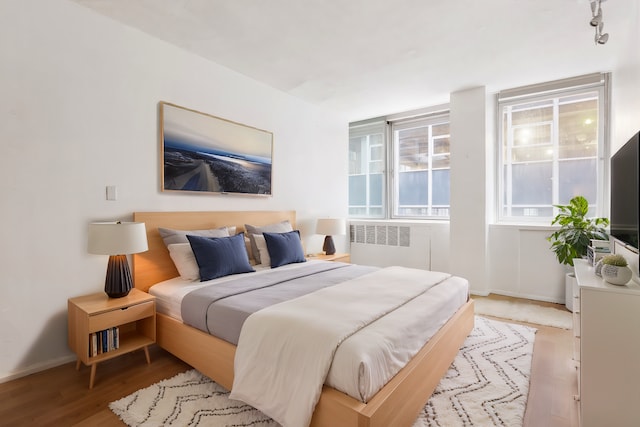 bedroom featuring radiator, wood finished floors, and baseboards