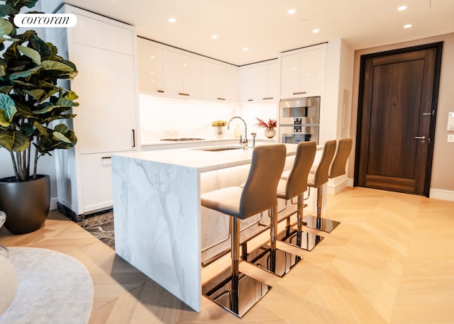 500 W 18th St Unit East17C, New York City, NY 10011 - kitchen with modern cabinets, white cabinetry, a kitchen breakfast bar, recessed lighting, and a center island with sink