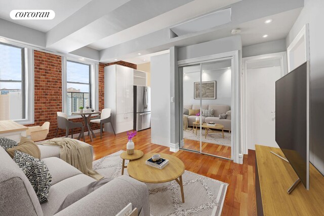living room with visible vents, recessed lighting, light wood-type flooring, and brick wall