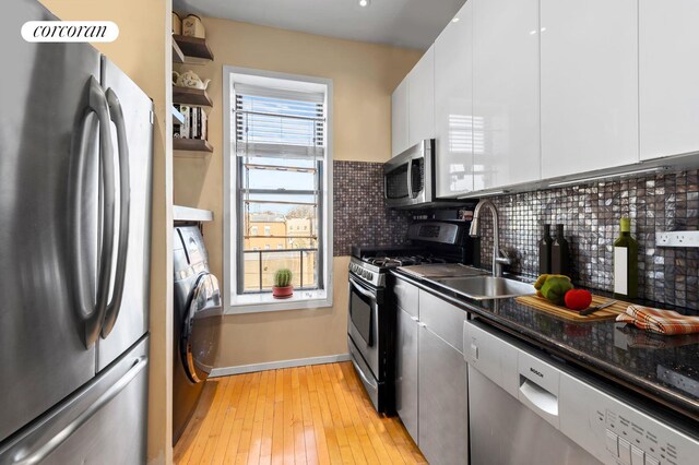 kitchen with washer / clothes dryer, tasteful backsplash, white cabinets, and appliances with stainless steel finishes
