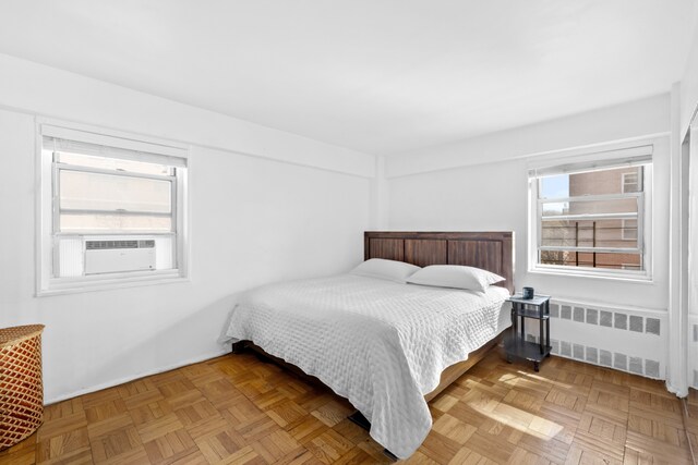 bedroom with cooling unit, radiator, and multiple windows