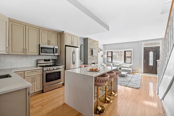 kitchen with open floor plan, light wood-style flooring, appliances with stainless steel finishes, and backsplash