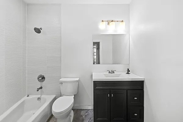 full bath featuring vanity, baseboards, washtub / shower combination, and toilet