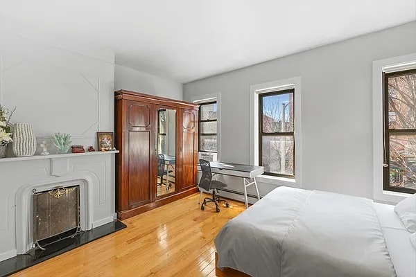 bedroom featuring multiple windows, light wood-style flooring, and a baseboard radiator